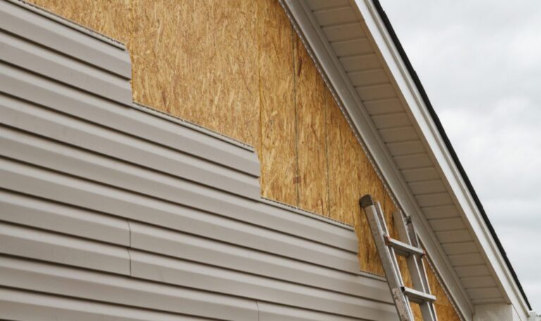 artially installed vinyl siding on a house with exposed wooden sheathing and a ladder leaning against the wall.